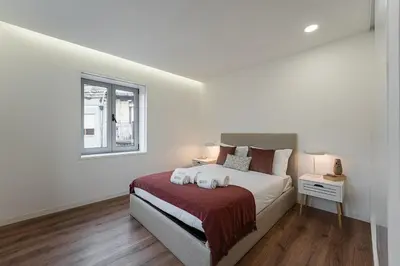 a white bedroom with a bed and a window at GuestReady - Urkunina apartment in Porto