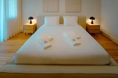 a bedroom with a large white bed with towels on it at The Cale - Porto, Firmeza 2 in Porto