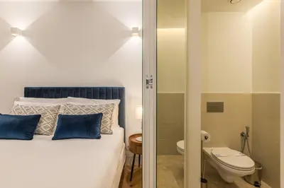 a bedroom with a bed with blue pillows and a toilet at Bailarina Historic Luxury House at Rua das Flores in Porto