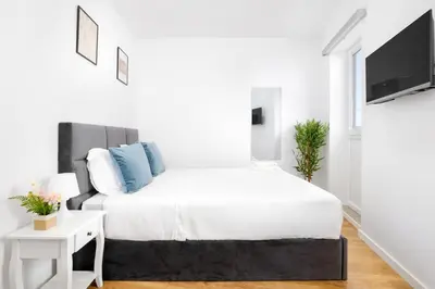 a white bedroom with a bed and a tv at Cozy Studio 2 min walk to Douro River with AC in Vila Nova de Gaia