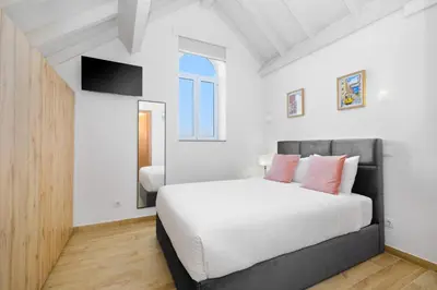 a bedroom with a white bed with pink pillows at Sunny House with Patio, Walk to Attractions in Vila Nova de Gaia