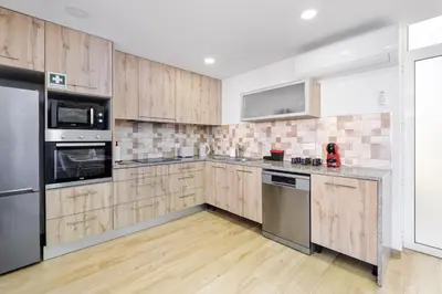a kitchen with wooden cabinets and stainless steel appliances at Sunny House with Patio, Walk to Attractions in Vila Nova de Gaia