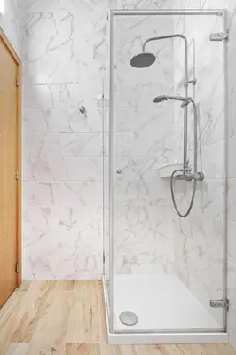 a shower in a bathroom with white marble walls at Sunny House with Patio, Walk to Attractions in Vila Nova de Gaia