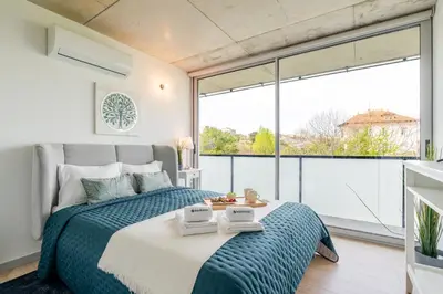 a bedroom with a bed and a large window at HostWise - Modern Flat w/ Balcony, Garage & Pool in Vila Nova de Gaia