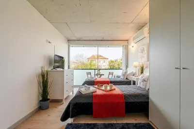 a bedroom with two beds and a table in it at HostWise - Modern Flat w/ Balcony, Garage & Pool in Vila Nova de Gaia