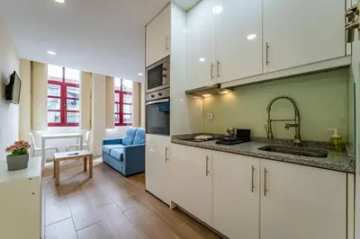 a kitchen with white cabinets and a blue couch at Close to Everything Your Oporto Blue PRM 2F in Porto