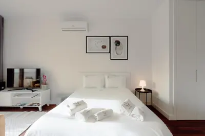 a white bedroom with a large bed and a living room at Almada 516 by Best2Stay in Porto