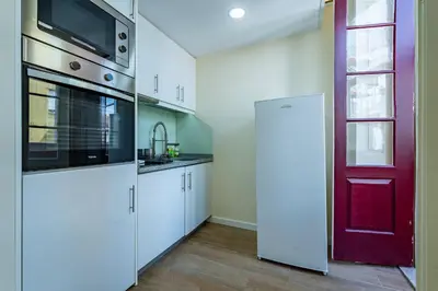 a kitchen with white cabinets and a red door at Close to Everything Your Oporto Terrace PRM 1T in Porto
