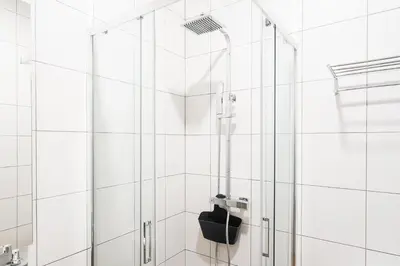 a shower with a black seat in a white bathroom at GuestReady – The Mythic Apartments in Porto
