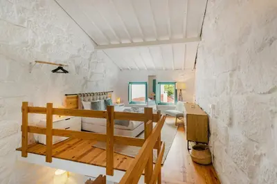 a room with a stone wall with a bed and a desk at GuestReady - A special place in Porto in Porto