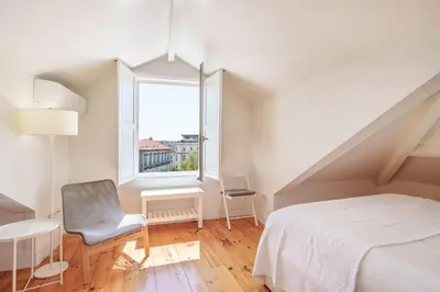 a bedroom with a bed and a chair and a window at VIVA Loft in Historic Center Porto in Porto