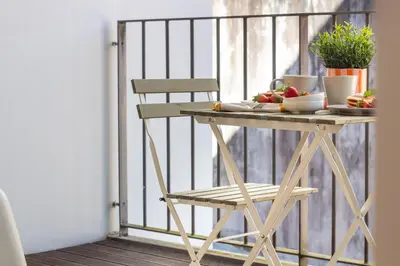 a table with a bowl of fruit and a chair on a balcony at Santa Teresa Studio by LovelyStay in Porto