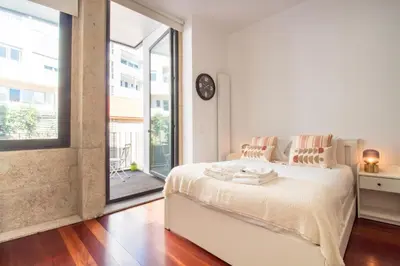 a bedroom with a white bed and a large window at Santa Teresa Studio by LovelyStay in Porto