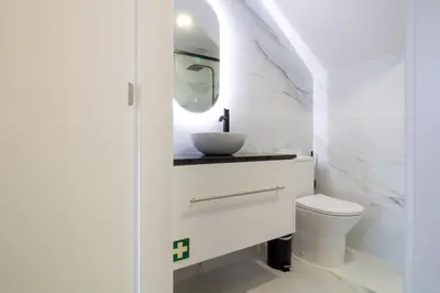 a white bathroom with a sink and a toilet at Quiet Duplex w Patio in Lapa by LovelyStay in Porto