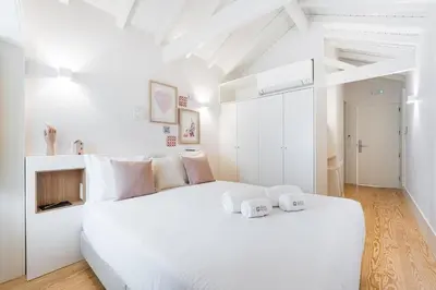 a white bedroom with a large white bed with two towels at GuestReady - Clérigos Tiles House in Porto