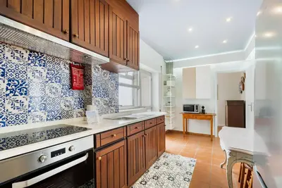 a kitchen with wooden cabinets and blue and white tiles at GuestReady - Peaceful retreat near Casa da Música in Porto