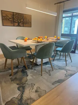 a dining room with a table and chairs on a rug at White Stripes House of Music in Porto