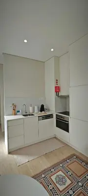 a kitchen with white cabinets and a sink and a rug at Apartamento D'Alegria in Porto
