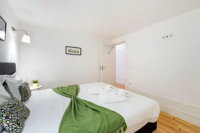 a bedroom with a large white bed with green sheets at GuestReady - Dolce experience in Porto in Porto