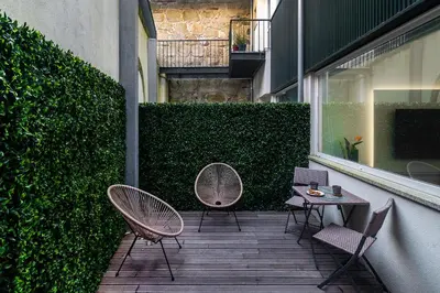 a patio with two chairs and a table and a hedge at WHome Modern Studio in Santa Catarina in Porto