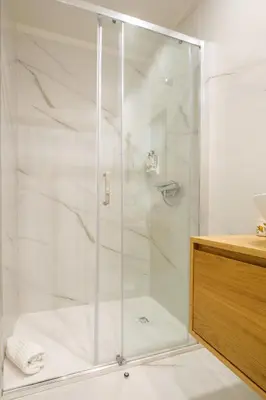 a shower with a glass door in a bathroom at Art Deco 32 Luxury 2BR Apartment Downtown Metro AC in Porto