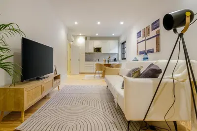 a living room with a white couch and a television at Art Deco 12 Luxury 2BR Apartment Downtown Metro AC in Porto