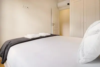 a white bed with two towels on top of it at Art Deco 22 Luxury 2BR Apartment Downtown Metro AC in Porto