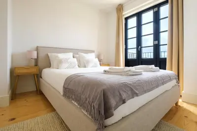 a bedroom with a bed with white sheets and a window at Art Deco 41 Luxury Apartment Downtown Metro AC in Porto
