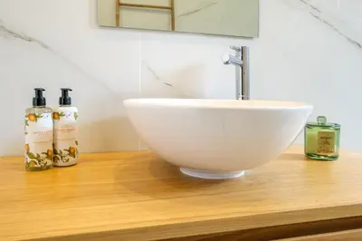 a white bowl sink on a wooden counter with two bottles at Art Deco 41 Luxury Apartment Downtown Metro AC in Porto