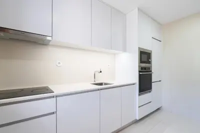 a white kitchen with white cabinets and a sink at Bright & Spacious Flat by Host Wise in Porto