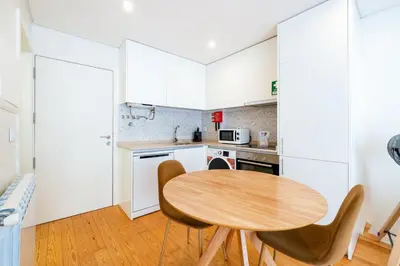 a small kitchen with a wooden table and chairs at GuestReady - Homely escape near Bolhão in Porto