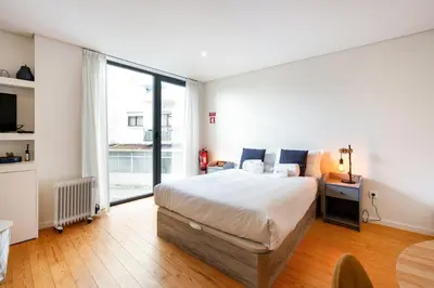 a bedroom with a large bed and a large window at GuestReady - Homely escape near Bolhão in Porto