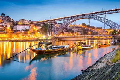 two boats are docked in the water under a bridge at Apartamento Camões in Porto
