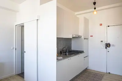 a kitchen with white cabinets and a sink at ApartmentsPorto - Boavista Delight Studio in Porto