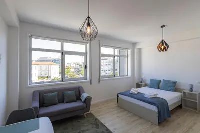 a bedroom with a bed and a couch and windows at ApartmentsPorto - Boavista Delight Studio in Porto