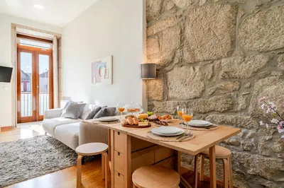 a living room with a table and a stone wall at HostWise - Stylish Flat with Balcony in Porto