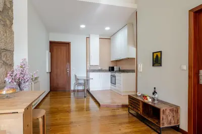 a kitchen and living room with white walls and wooden floors at HostWise - Stylish Flat with Balcony in Porto