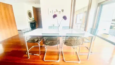 a glass table with chairs and a vase with purple flowers at VER Torrinha -Porto in Porto