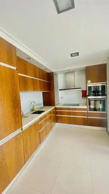 a kitchen with wooden cabinets and a white tile floor at VER Torrinha -Porto in Porto