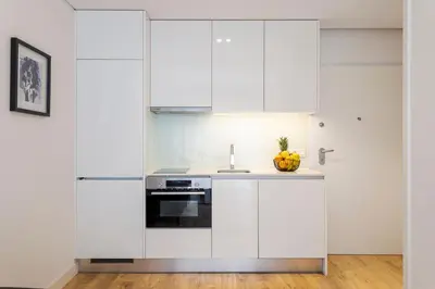 a kitchen with white cabinets and a sink at Studio w/ Terrace, Pool & Gym | Antas by Host Wise in Porto