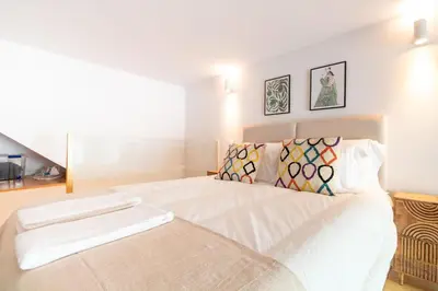 a bedroom with a large white bed with two pillows at Cozy Mezzanine Hideaway w AC by LovelyStay in Porto