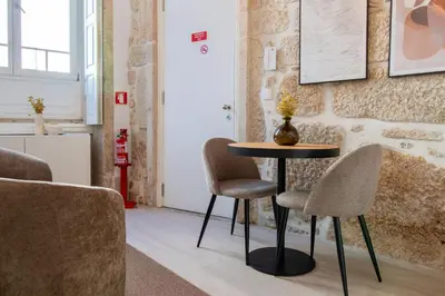 a table and chairs in a room with a wall at Cozy Mezzanine Hideaway w AC by LovelyStay in Porto