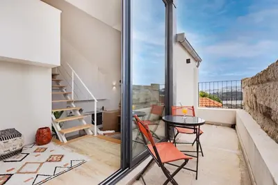 a living room with a table and a couch and a staircase at Saldanha Boho Duplex in Porto
