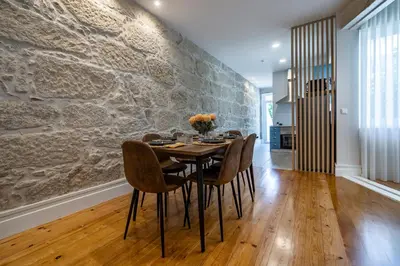 a dining room with a stone wall and a table and chairs at ApartmentsPorto - Porto Dukes House in Porto