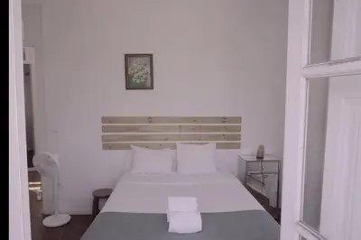 a white bedroom with a bed with white sheets and pillows at Light & Airy Historic Centre House with Balconies in Porto