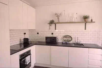 a kitchen with white cabinets and a black counter top at Light & Airy Historic Centre House with Balconies in Porto