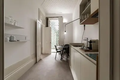 a kitchen with white cabinets and a table in it at Malmerendas Boutique Lodging in Porto