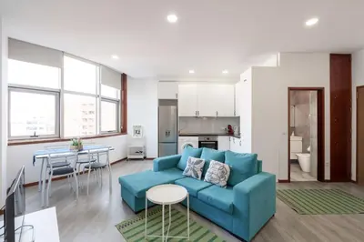 a living room with a blue couch and a kitchen at VIVA Cozy Nest Studio Porto in Porto
