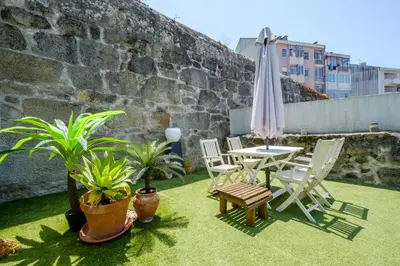 a patio with a table and chairs and an umbrella at Bonfim Garden Apartment Near Metro & City Center in Porto