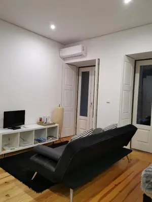 a living room with a black couch and a tv at Your Place Porto II in Porto